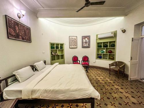 a bedroom with a large bed in a room with chairs at DYORE House by Bharat Mahal Palace in Jaipur