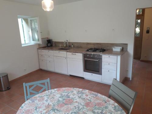 une cuisine avec une table, un évier et une cuisinière dans l'établissement La Maison Cassée, à Malemort-du-Comtat