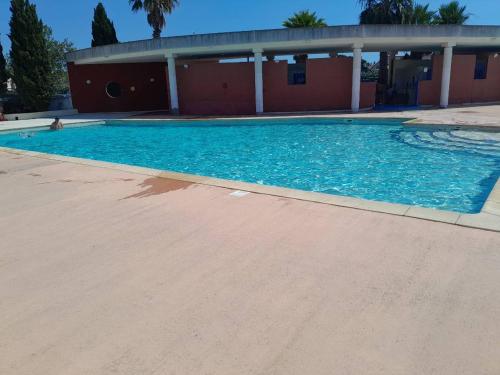 une piscine avec de l'eau bleue devant un immeuble dans l'établissement Clos Gabmy entre plage et garrigue, à Vic-la-Gardiole