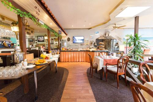 a restaurant with tables and chairs and a counter at Hotel Garni Am Deich in Zingst