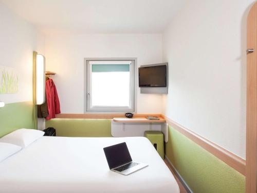 a room with a bed with a laptop on it at ibis budget Beaconsfield in Beaconsfield