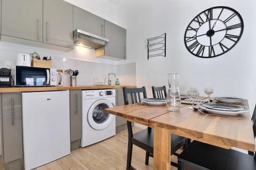 a kitchen with a table and a clock on the wall at Le St Clair 403 - Luxury & fully equipped apartment - Caluire-et-Cuire in Caluire-et-Cuire