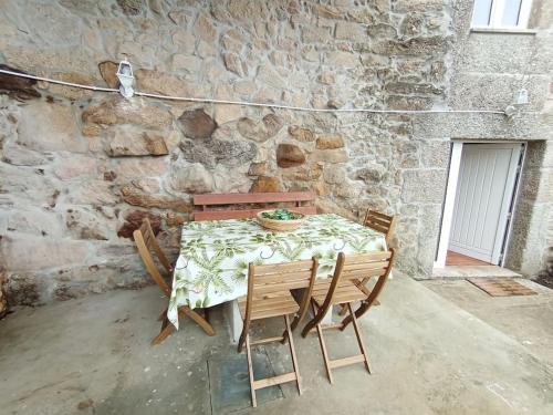 einen Tisch mit Stühlen und eine Steinmauer in der Unterkunft casa dos Ferreira no Douro in Ucanha