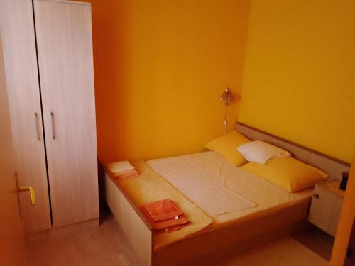 une petite chambre avec un lit aux murs jaunes dans l'établissement Apartments Velo, à Veli Lošinj