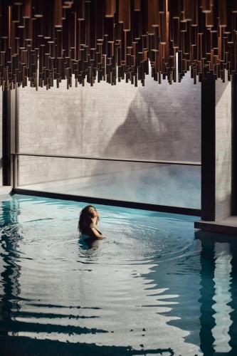 a woman swimming in a pool under a chandelier at Six Senses Crans-Montana in Crans-Montana