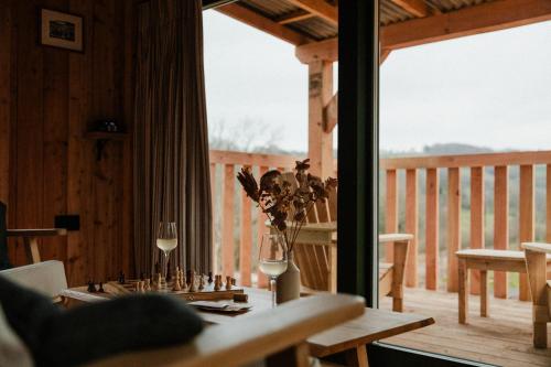 a table with two glasses of wine on a deck at The Bulls Head Wild Cabins in Hereford