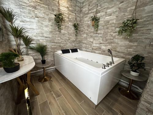 - une baignoire blanche dans une pièce ornée de plantes dans l'établissement Pentagone 1 SPA PRIVE, à Reims
