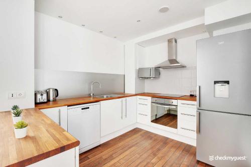 une cuisine avec des armoires blanches et un réfrigérateur en acier inoxydable dans l'établissement Charming home Convention Serres, à Paris