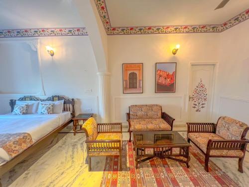 a bedroom with a bed and two chairs and a table at DYORE House by Bharat Mahal Palace in Jaipur
