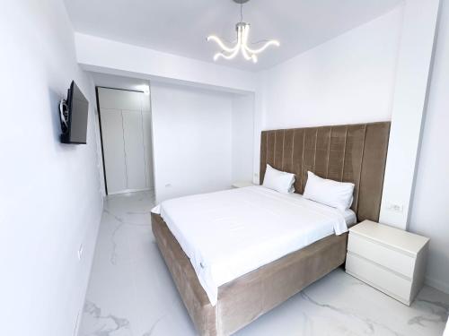 a white bedroom with a large bed and a mirror at Wave 6 Apartments in Năvodari