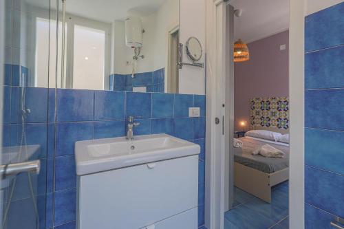 een blauwe betegelde badkamer met een wastafel en een slaapkamer bij Amami Home in Salerno