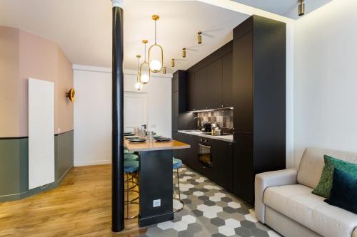 une cuisine avec des placards noirs, une table et un canapé dans l'établissement Charming Flat - 2BD-8P - Charonne-Bastille, à Paris