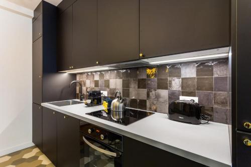 une cuisine avec des armoires noires et un comptoir dans l'établissement Charming Flat - 2BD-8P - Charonne-Bastille, à Paris