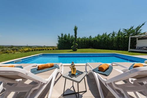a villa with a swimming pool with white chairs at Villa Lux ZadarVillas in Donji Zemunik