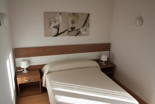 een kleine slaapkamer met een bed en twee nachtkastjes bij Alojamiento Ubaldo Nieto in Carracedo del Monasterio