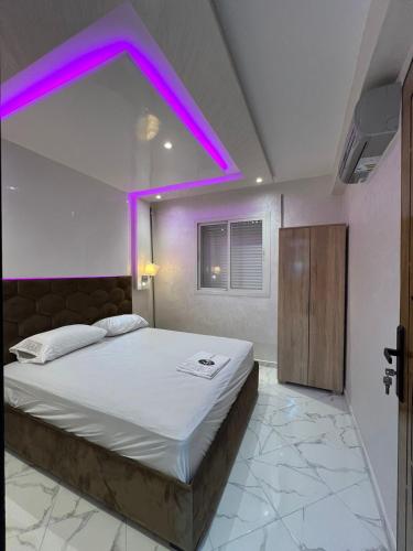 una camera da letto con un grande letto con illuminazione viola di appartement riad sofia a Martil