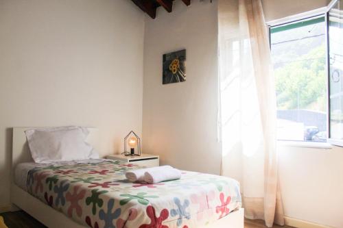 a bedroom with a bed with a lamp and a window at House 37North in Mosteiros
