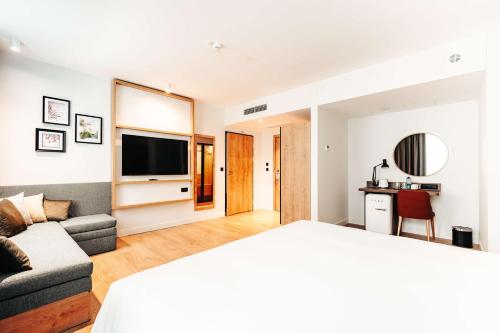a room with a bed and a couch and a television at Hilton Garden Inn Radom in Radom