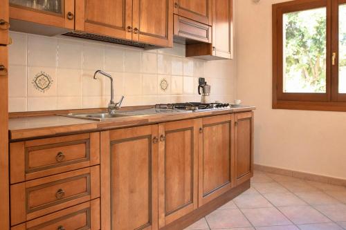 a kitchen with wooden cabinets and a sink and a window at Residence con piscina a Sos Alinos in Cala Liberotto