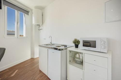 a white kitchen with a sink and a microwave at Casa Milano 3 in Jerez de la Frontera
