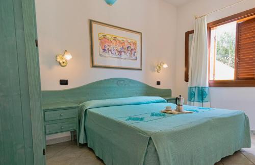 a bedroom with a green bed and a dresser at Residence con piscina a Sos Alinos in Cala Liberotto