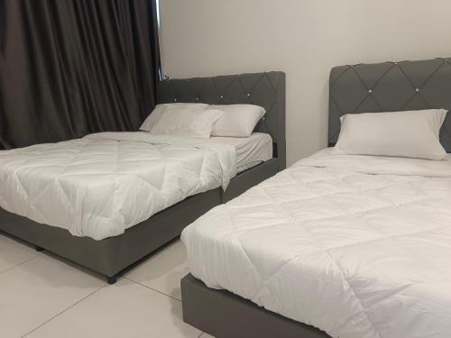 two beds sitting next to each other in a bedroom at Familystay Home 3BR-10PAX in Gua Sai