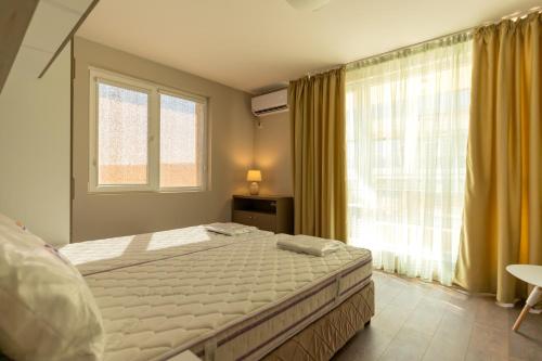 a bedroom with a bed and a large window at Swan Bay complex in Chernomorets