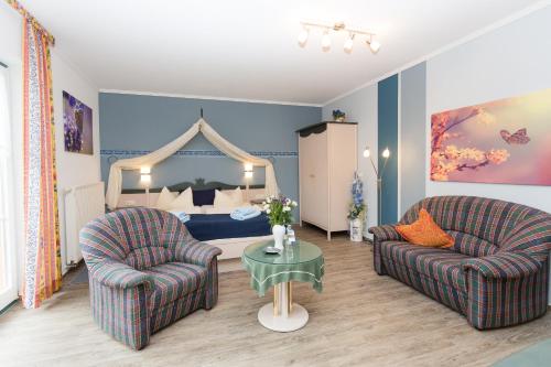 a living room with two chairs and a bed at Hotel Garni Am Deich in Zingst