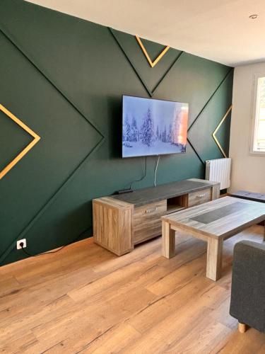 a living room with a table and a tv on a wall at Residence coeur de vallée in Albertville