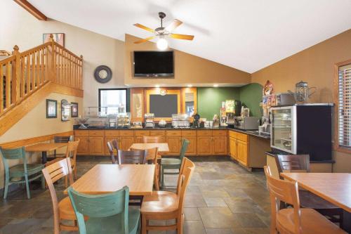 a restaurant with tables and chairs and a kitchen at AmericInn by Wyndham Ankeny/Des Moines in Ankeny