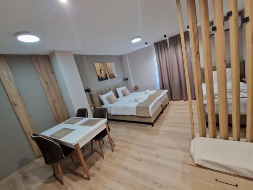 a room with two beds and a table and a desk at Hotel CENTRAL in Prilep