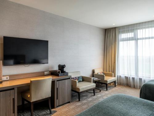 a hotel room with a desk with a television and chairs at Van Der Valk Hotel Zwolle in Zwolle