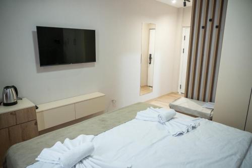 a bedroom with a white bed with a tv on the wall at Hotel CENTRAL in Prilep