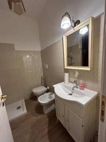 a bathroom with a sink and a toilet and a mirror at Relais La Villa in Lucera