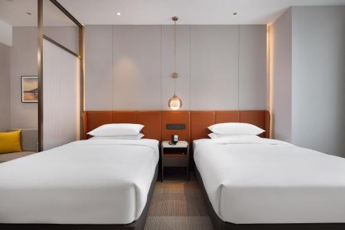 a room with two beds and a table at Home2 Suite by Hilton Wuhan Economic Development Zone in Wuhan
