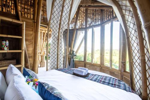 a bed in a room with a large window at Magic Hills Bali - Eco Luxury Adventure in Karangasem