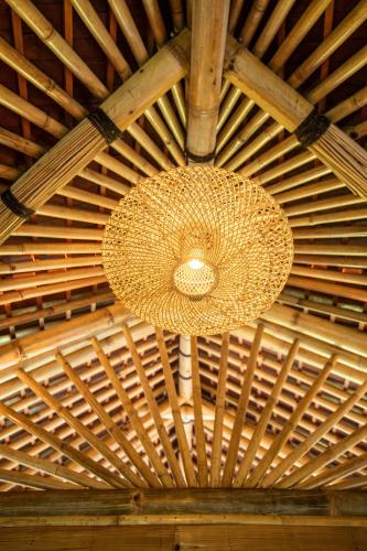 a ceiling with a light fixture hanging from a wooden ceiling at Magic Hills Bali - Eco Luxury Adventure in Karangasem