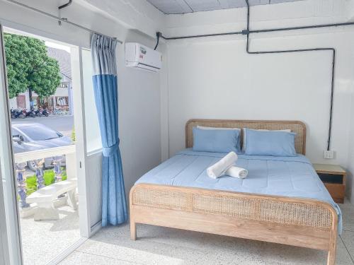 a bedroom with a bed with blue sheets and a window at Bangsaphan Resort in Bang Saphan