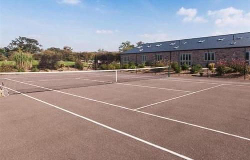 a tennis court with a net in front of a building at Luxury Barn near Wells - Pool, Gym in Wells