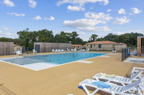 une piscine avec des chaises longues blanches et une piscine dans l'établissement Chalet familial avec SPA, à Saubrigues