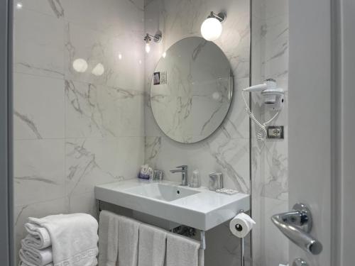 a white bathroom with a sink and a mirror at Hotel Maxim Axial in Florence