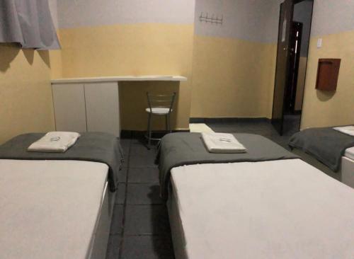 two beds in a room with a desk and a chair at Hotel Sany SP- Metrô Paulista in Sao Paulo