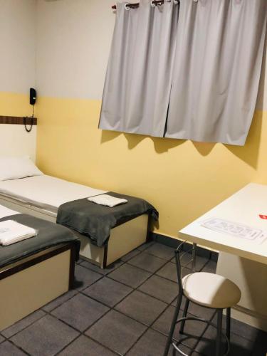 a room with two beds and a table and a window at Hotel Sany SP- Metrô Paulista in Sao Paulo