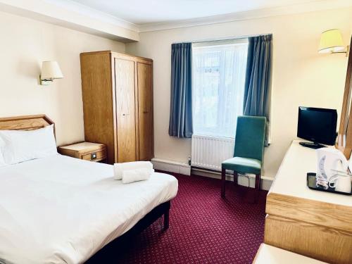 a hotel room with two beds and a chair and a window at Carrington House Hotel in Bournemouth