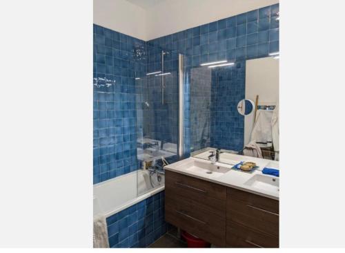 une salle de bain carrelée bleue avec un lavabo et une baignoire dans l'établissement Chambre vue mer, à Marseille