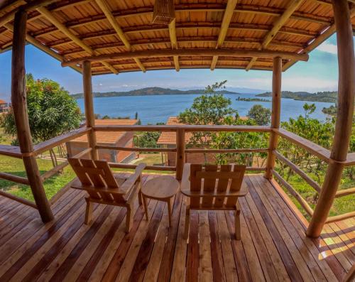 a wooden deck with two chairs and a table on it at Umutuzo Lodge Kivu Lake in Buhoro