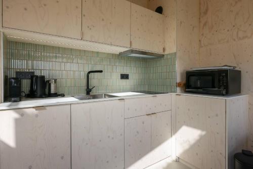 a kitchen with a sink and a microwave at Hello Zeeland - Tiny House Zeeuwse Liefde 5 in Westkapelle