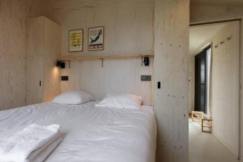a bedroom with a large bed with white sheets at Hello Zeeland - Tiny House Zeeuwse Liefde 5 in Westkapelle