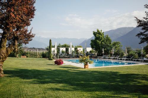 a swimming pool in a yard with mountains in the background at Hotel Gantkofel in Andrian