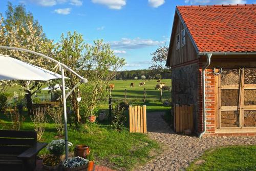 Un pequeño edificio con un campo de vacas al fondo. en Ferienwohnung Alte Schule Chorin Schorfheide, en Chorin
